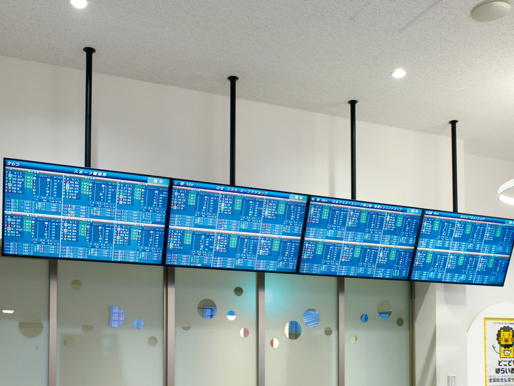 写真：入り口すぐの壁面にはTH-55LFE8Jが8台横並びに設置。8場分のオッズ情報や成績がリアルタイムに表示される